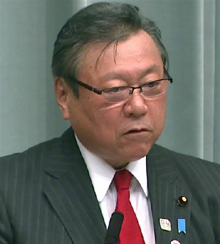 Middle-aged man in glasses and suit speaking at a podium, presenting facts for learning new things and new facts.