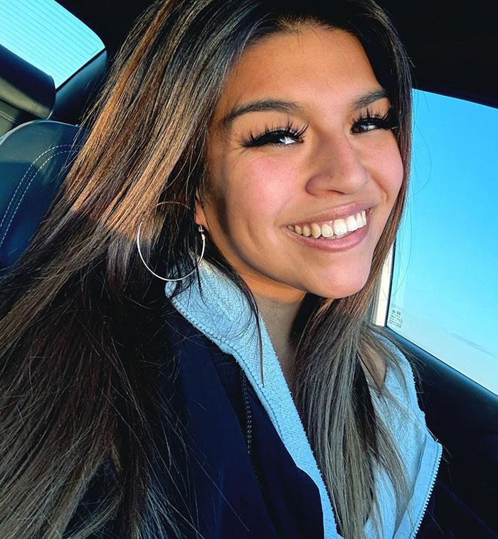 Young woman smiling inside car, representing the story involving car damage by pouring salt in engine and glitter in AC.
