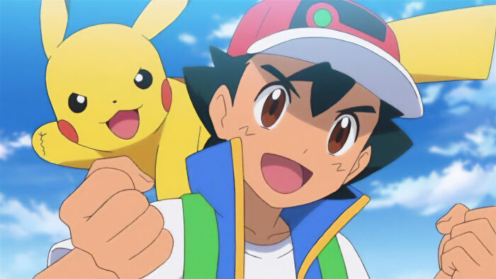Anime character Ash Ketchum with Pikachu on his shoulder, shown outdoors with blue sky background.