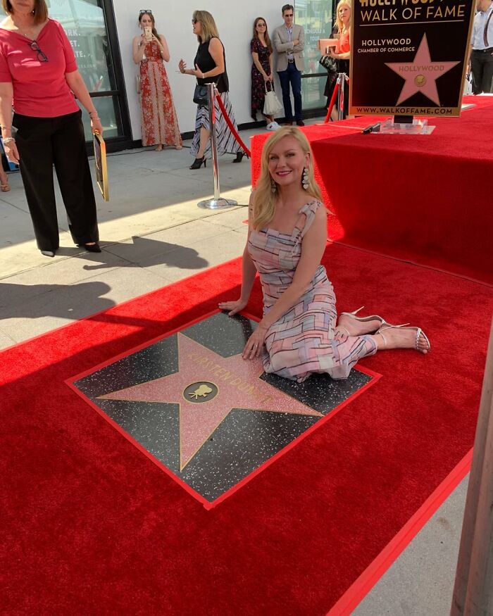 Kirsten Dunst kneeling beside her Hollywood Walk of Fame star during the unveiling ceremony on a sunny day. Kirsten Dunst kneeling beside her Hollywood Walk of Fame star during the unveiling ceremony on a sunny day.