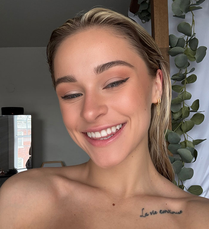 Smiling young woman with gold earrings and sleek hair, representing a 23-year-old quitting $180k job over gross comments.