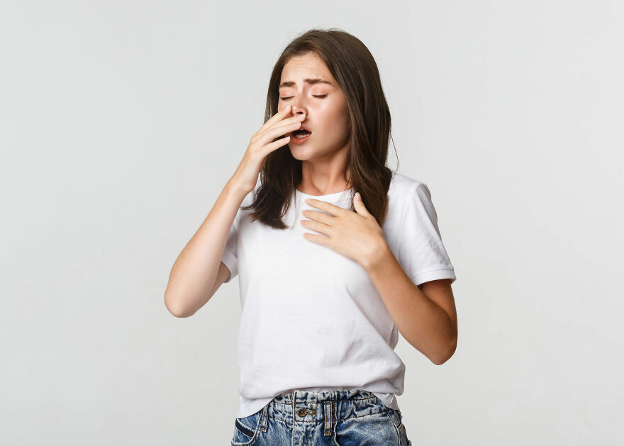 Young woman in white shirt holding chest and covering mouth, illustrating neurologist warning about stroke and dementia risks
