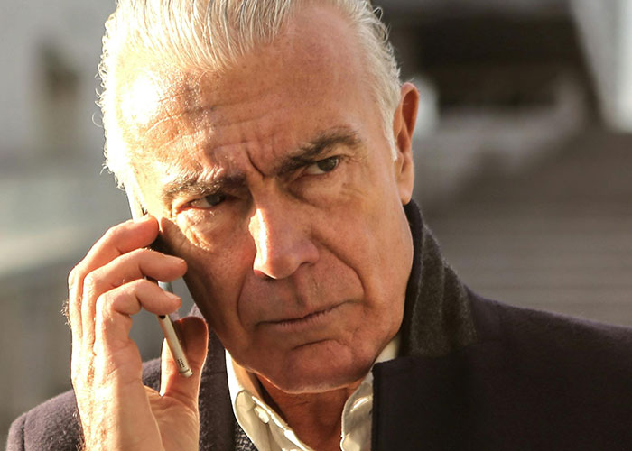 Elderly man looking concerned while on a phone call, illustrating man gets sick after eating food dad touched.