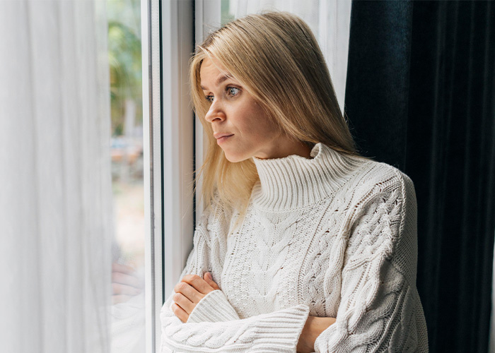 Blonde woman in a white sweater looking thoughtfully out the window reflecting on moments rich people realized normal life differs. - 8