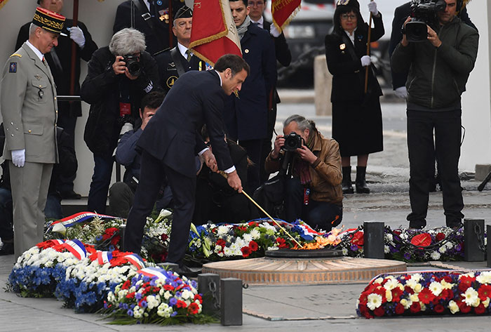 Man lighting the flame at the Tomb of the Unknown Soldier while officials and photographers observe nearby. - 2