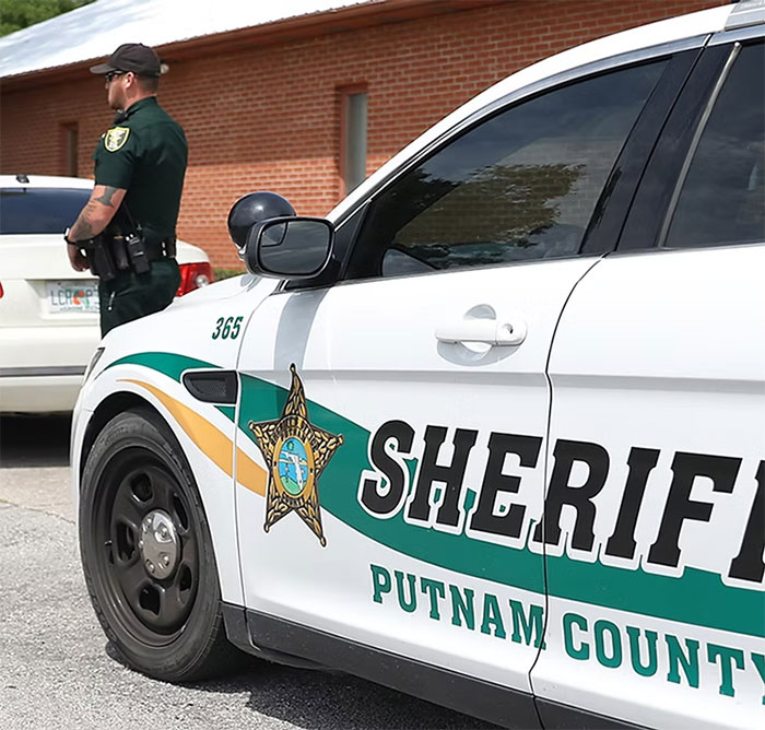 Putnam County sheriff car with officer standing nearby, related to Florida mother abandoning child and seven dogs case.