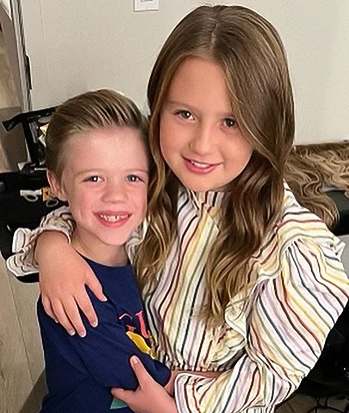 Two children smiling and hugging indoors, highlighting a family moment related to Brandon Blackstock&rsquo;s obituary mention.