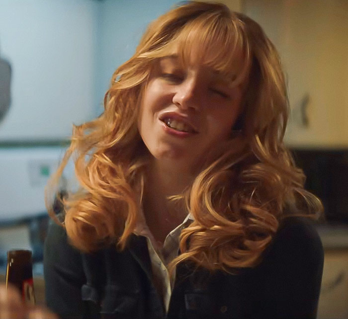 Sydney Sweeney with long curly hair in a casual setting reacting emotionally amid social media trolling controversy.