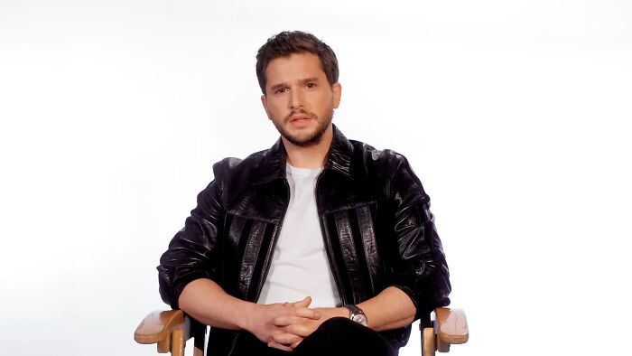 Actor Kit Harington sitting in a chair wearing a black leather jacket and white shirt, representing celebrities Hollywood tried to make leading.