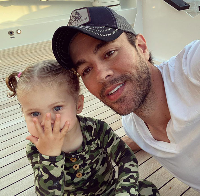 Enrique Iglesias posing with a young child on a wooden deck, highlighting family moments with Anna Kournikova. Enrique Iglesias posing with a young child on a wooden deck, highlighting family moments with Anna Kournikova.