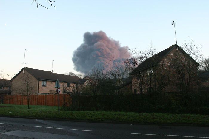 Smoke rising over suburban houses at dusk, capturing the chilling atmosphere of the scariest sounds ever heard by people at night.