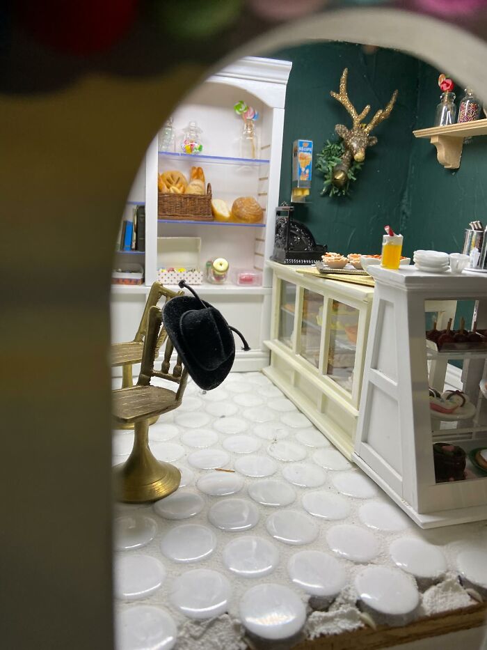 Miniature home decor pieces including a black hat on a chair and a detailed bakery setting with magical decor accents.