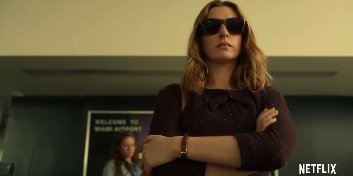 Woman wearing sunglasses with arms crossed at an airport, representing Netflix movies that turned out to be total letdowns.
