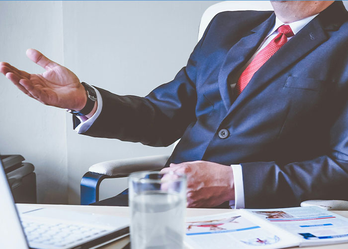 Man in a business suit gesturing with hand during office meeting, representing jobs without a soul concept.