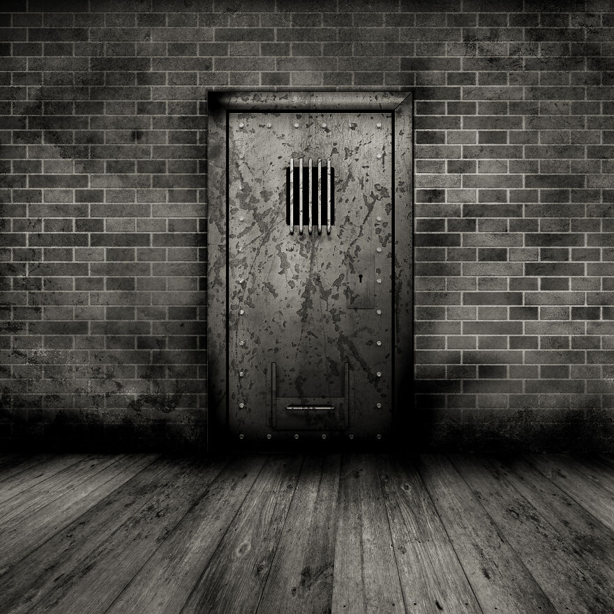 Rusty metal prison door with small barred window set in a brick wall, evoking claustrophobia and tight enclosed spaces. Rusty metal prison door with small barred window set in a brick wall, evoking claustrophobia and tight enclosed spaces.