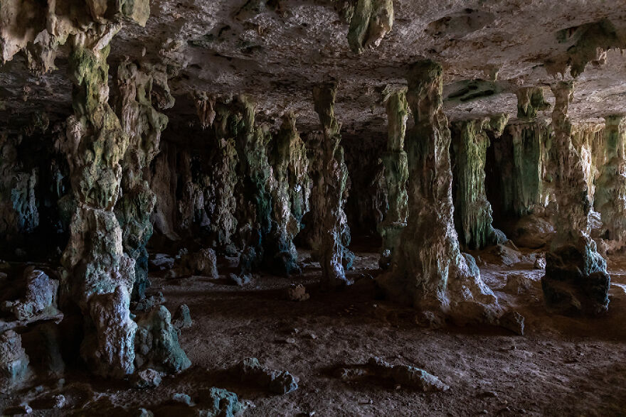 Dark cave interior with narrow stalagmites and stalactites creating an eerie claustrophobia atmosphere. Dark cave interior with narrow stalagmites and stalactites creating an eerie claustrophobia atmosphere.