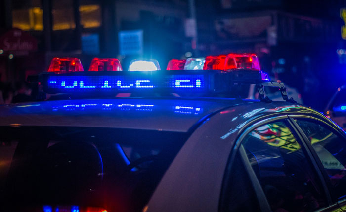 Police car with flashing lights at night, illustrating bar staff and customers protecting women from harassment.