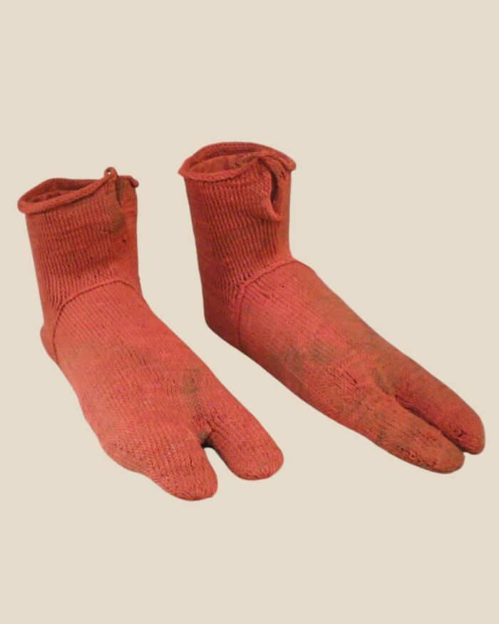 Pair of ancient red split-toe socks showcasing unfamiliar parts of history with unique textile design and craftsmanship.