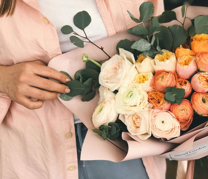 Person holding a colorful bouquet of flowers, representing a unique gesture that makes Americans stand out abroad.