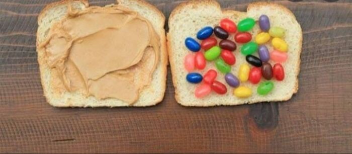 Two slices of white bread, one topped with peanut butter and the other with colorful jelly beans, illustrating unhealthy food choices.