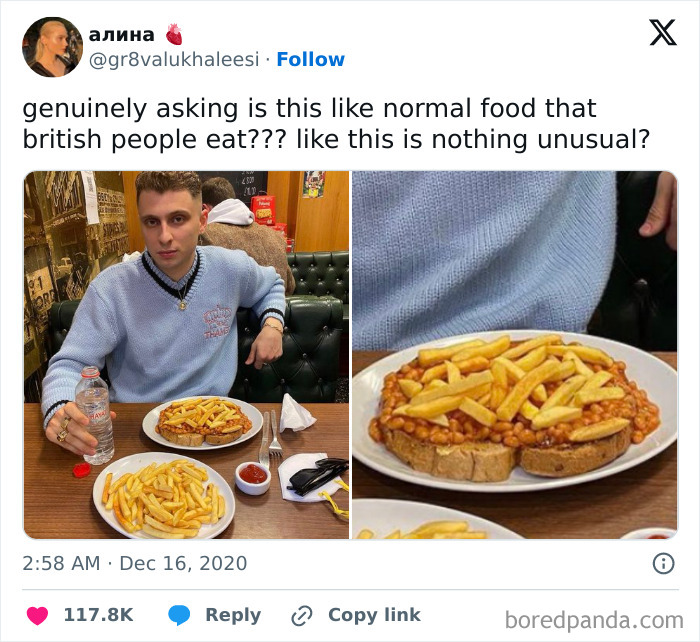 Young man sitting at a table with a plate of British beans on toast topped with fries, a chaotic British meme on food culture.
