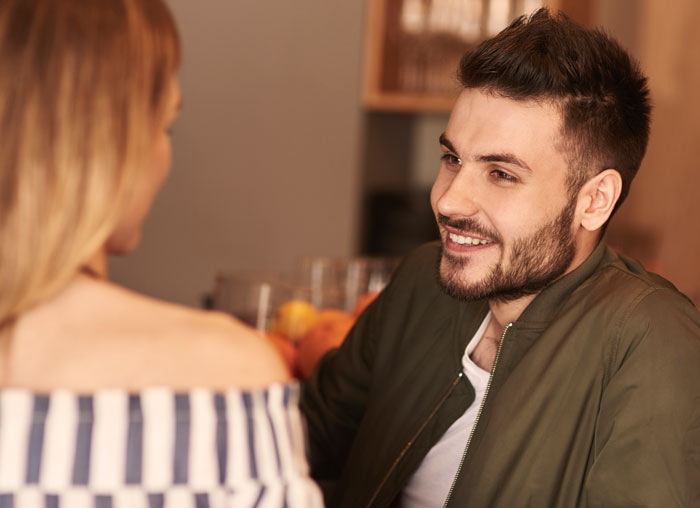 Man smiling and talking to woman in a casual setting illustrating man tells wife she couldn&rsquo;t do it without him concept.