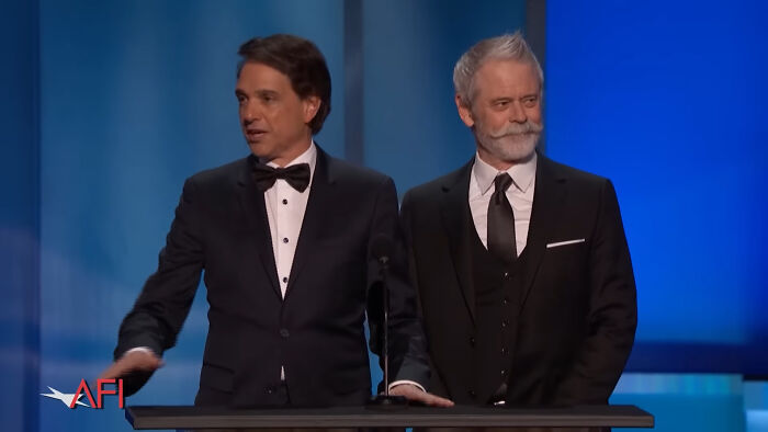 Two men in black tuxedos presenting on stage at a Hollywood event about celebrities not becoming leading A-listers.