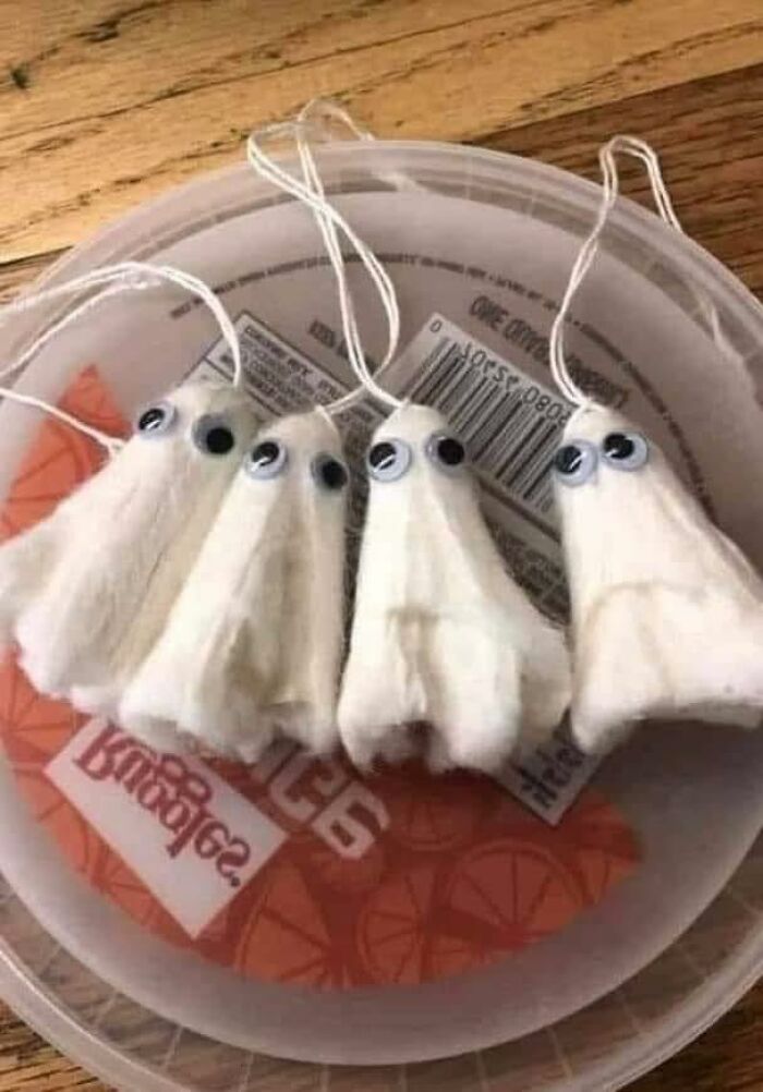 DIY craft project of small ghosts made from cotton balls with googly eyes, showcasing craft shaming humor and creativity gone wrong.