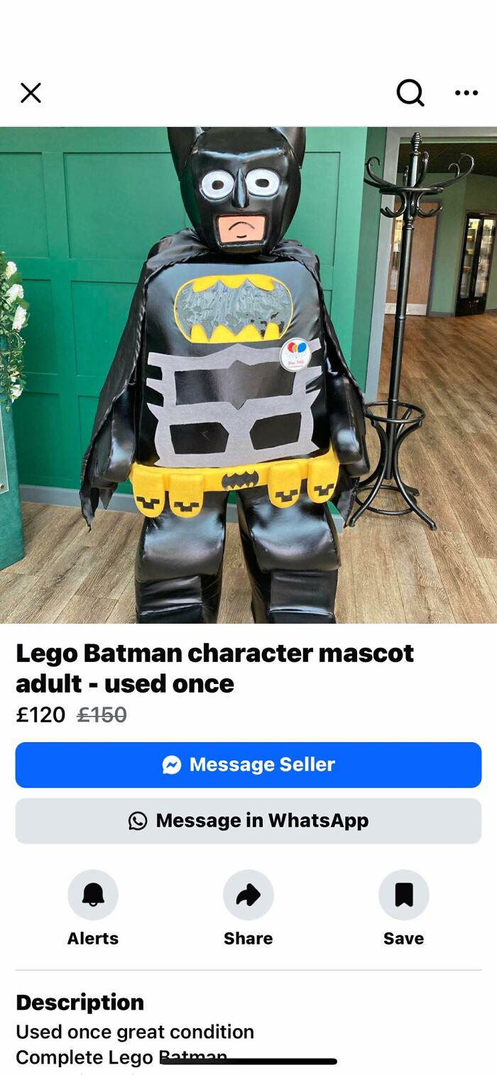 Adult Lego Batman costume DIY project with poorly crafted details, displayed in an indoor setting with wooden flooring and green wall.