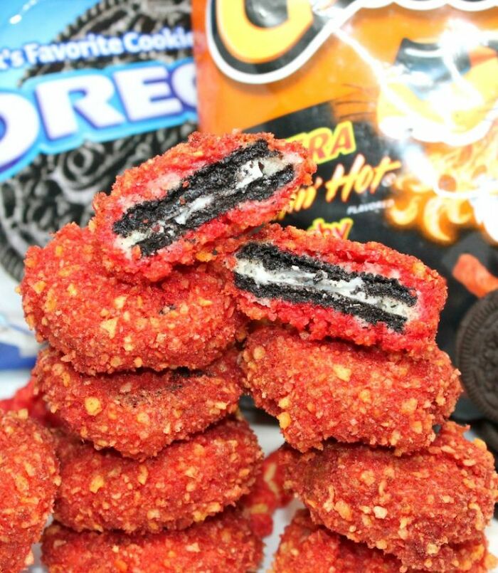 Deep-fried spicy coated cookies stacked with Oreo and Flamin' Hot Cheetos bags in the background, unhealthy food concept.