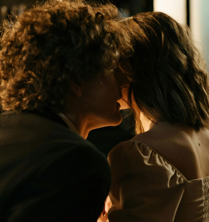 A man whispering closely to a woman in a dimly lit setting, illustrating situations bar staff protect women from harassment.