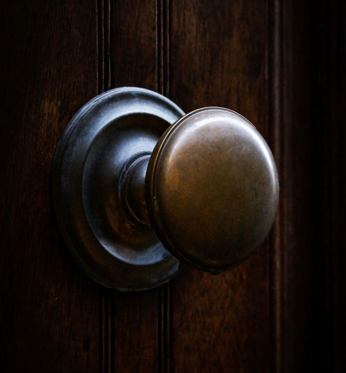 Close-up of a vintage door k**b on a dark wooden door, emphasizing home security and camera surveillance themes.
