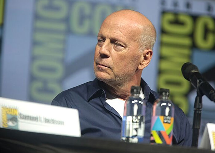 Bruce Willis speaking at a Comic-Con panel, showcasing a total gentleman moment during a celebrity encounter.