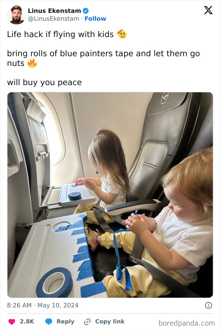 Two kids using blue painters tape on airplane tray tables as a genius life hack to keep them entertained during a flight.