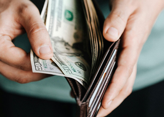 Hands holding a wallet with cash, representing jobs that only a person without a soul would do, involving money exchange.