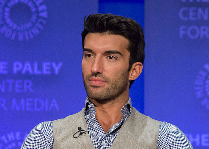 Man with dark hair wearing a gray vest and checkered shirt at a media event about celebrity encounters and experiences.