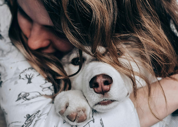 Woman hugging a dog closely, illustrating warmth and comfort in a casual, emotional moment about wild and embarrassing drinking stories.