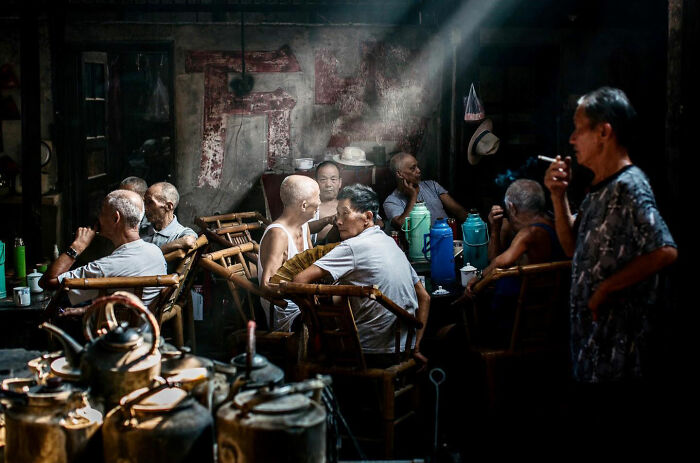 Elderly men gathered in an Asian tea house, sharing candid everyday moments captured by photographer Gil Kreslavsky.