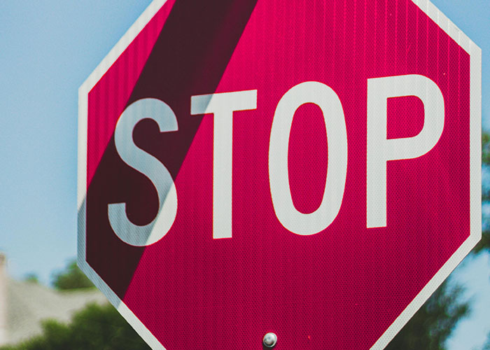 Close-up of a red stop sign against a blue sky, illustrating traffic rules related to driving over the speed limit.