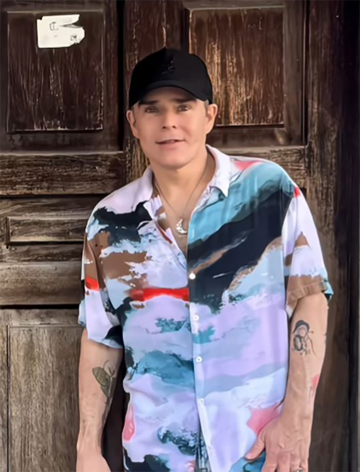 Man smiling in colorful shirt and black cap standing against a wooden door after a Mexico facelift reveal. Man smiling in colorful shirt and black cap standing against a wooden door after a Mexico facelift reveal.