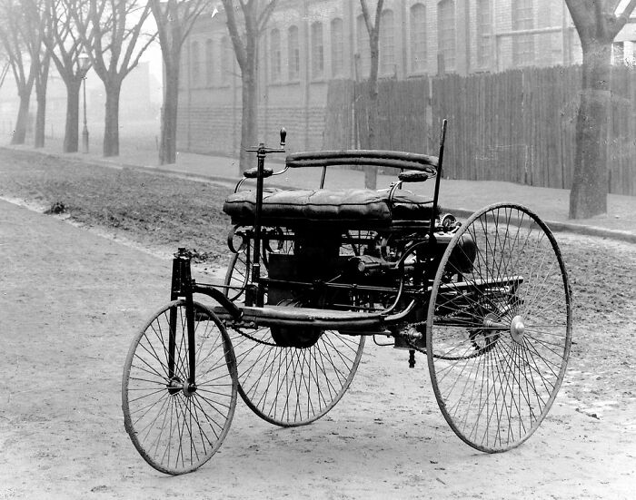 Early model first car on a dirt road showcasing wild and primitive automotive design from 100 years ago.