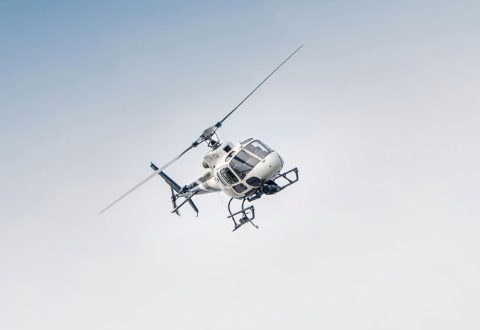White helicopter flying in the sky, an example of an insane family flex that might make you feel jealous.
