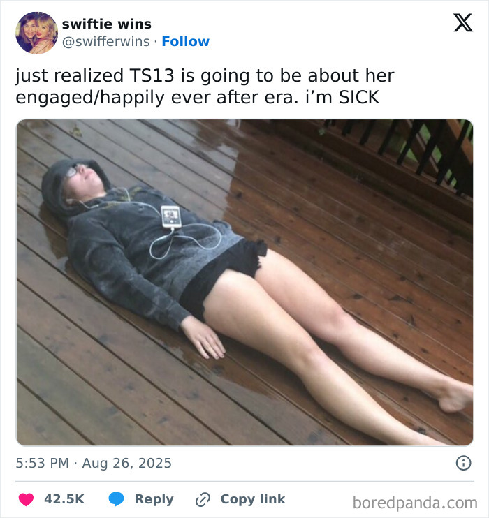 Person lying on wooden deck wearing hoodie and shorts, reacting to Taylor Swift engagement memes and fan reactions.