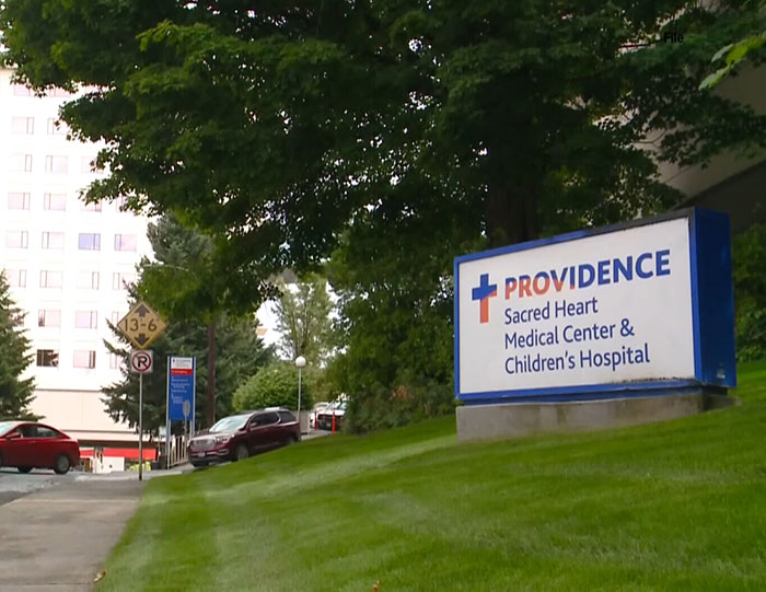 Providence Sacred Heart Medical Center entrance with sign, related to hospital firing 15 nurses after patient suicide.