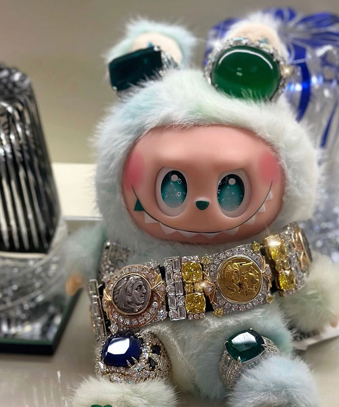Labubu doll dressed in fluffy attire wearing an expensive glass ceiling and chandelier inspired jewelry.