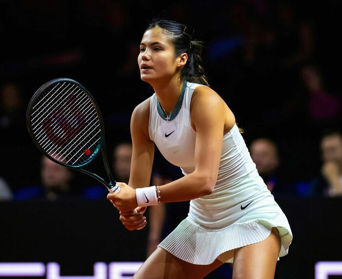 Tennis star preparing to return serve during a match amid a crowd stunned by a meltdown over crying baby distractions.