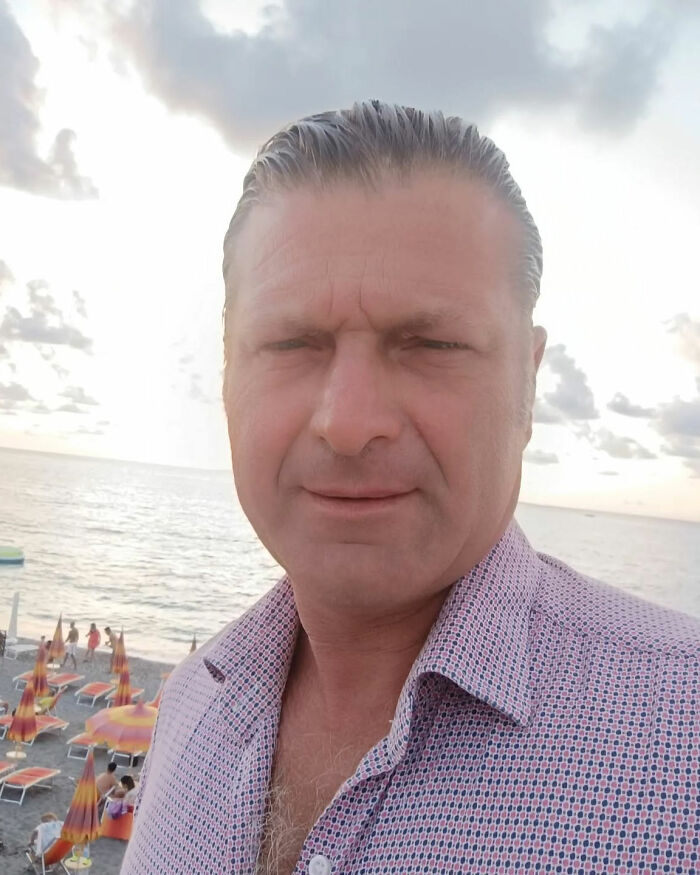 Man in patterned shirt at beach during sunset, linked to toxic broccoli sandwich incident under investigation by authorities.