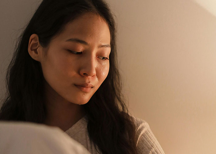 Mujer pensativa con insomnio en habitación tenue, reflejando datos inquietantes para reflexionar antes de dormir.