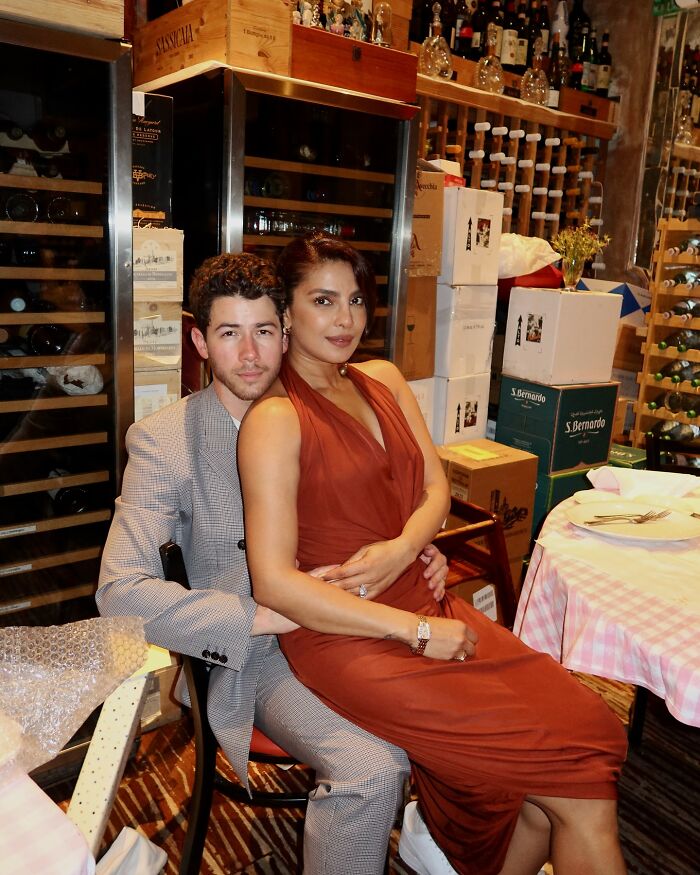 Nick Jonas and wife sitting in restaurant, spotlight on Nick Jonas revelation about never sitting in bed with his wife. Nick Jonas and wife sitting in restaurant, spotlight on Nick Jonas revelation about never sitting in bed with his wife.