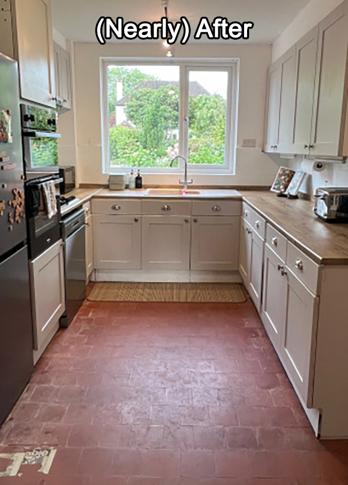 Clean DIY kitchen makeover with white cabinets, wooden countertops, and natural light from a large window over the sink.